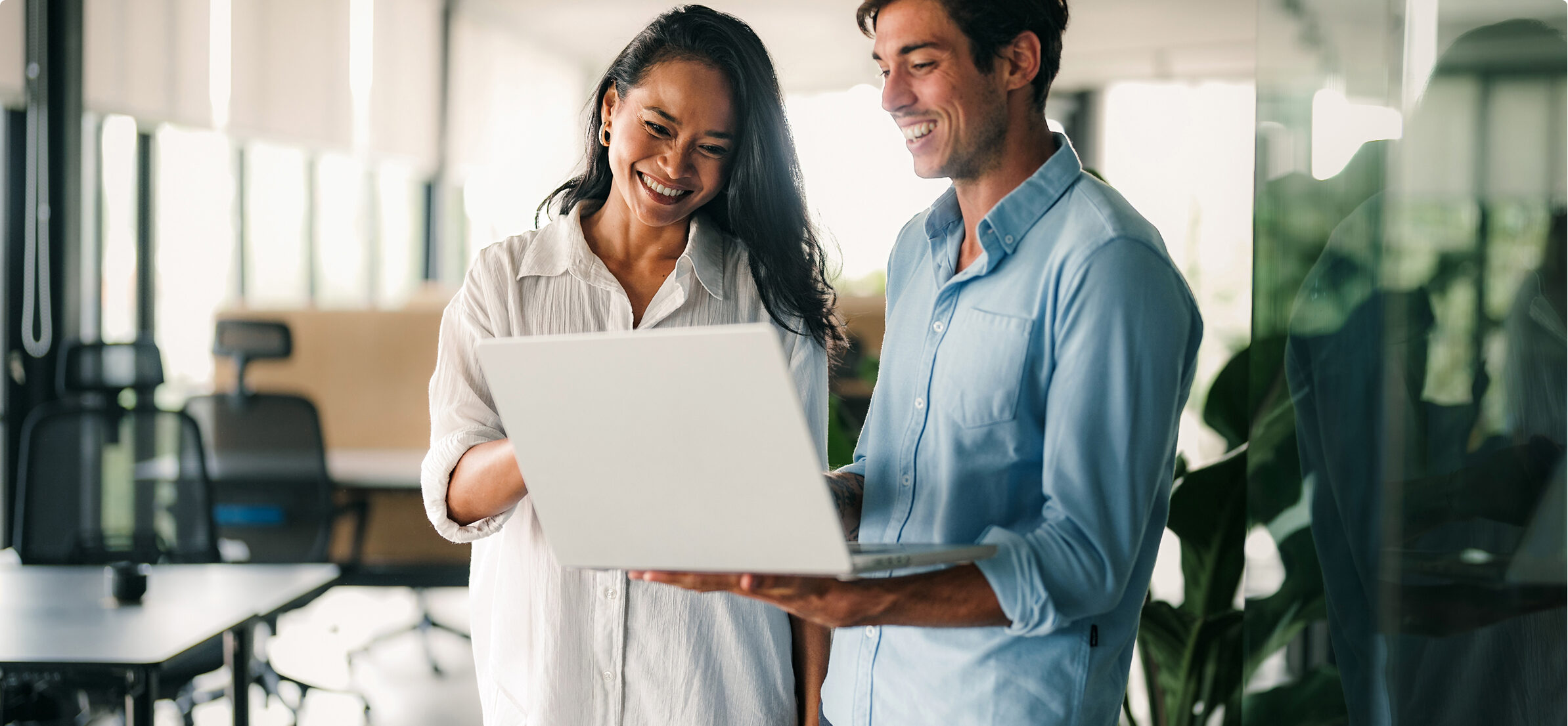 Woman and man look at laptop together in an office.