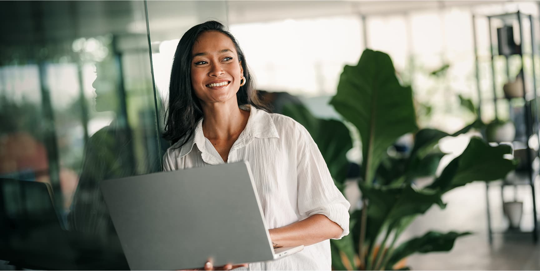 Woman smiling with laptop in an office space.